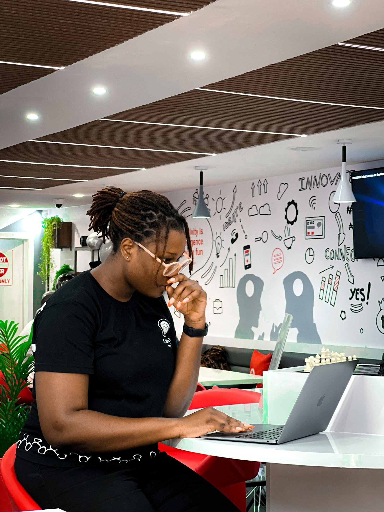 A young African Fellow focused on her laptop at a tech hub